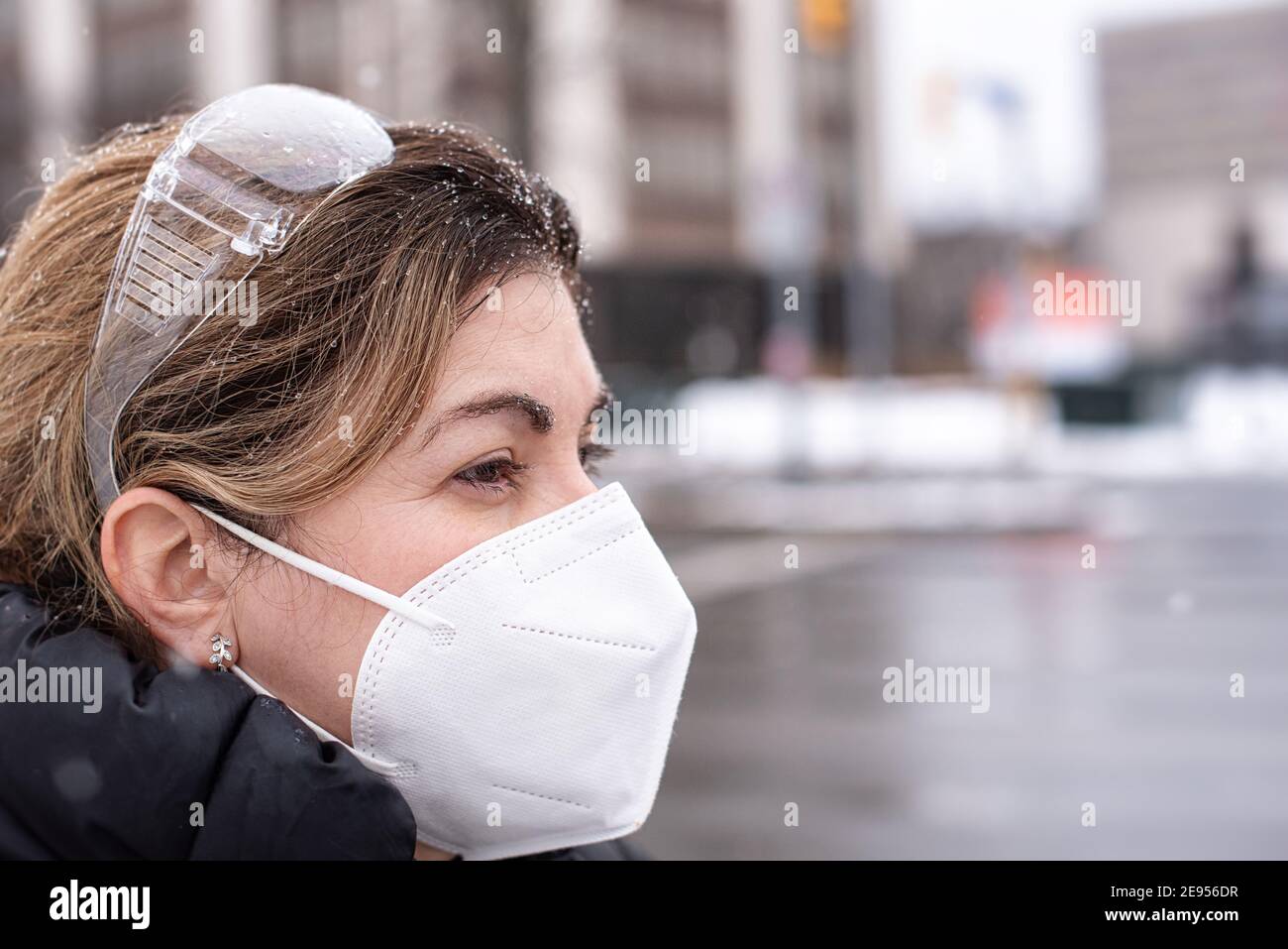 Covid-19 o Coronavirus, una mujer que lleva una máscara protectora en invierno, Canadá, 2021 Foto de stock