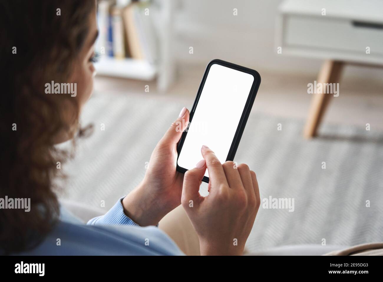 Mujer joven mano sosteniendo el teléfono inteligente tocando la pantalla en blanco. Foto de stock
