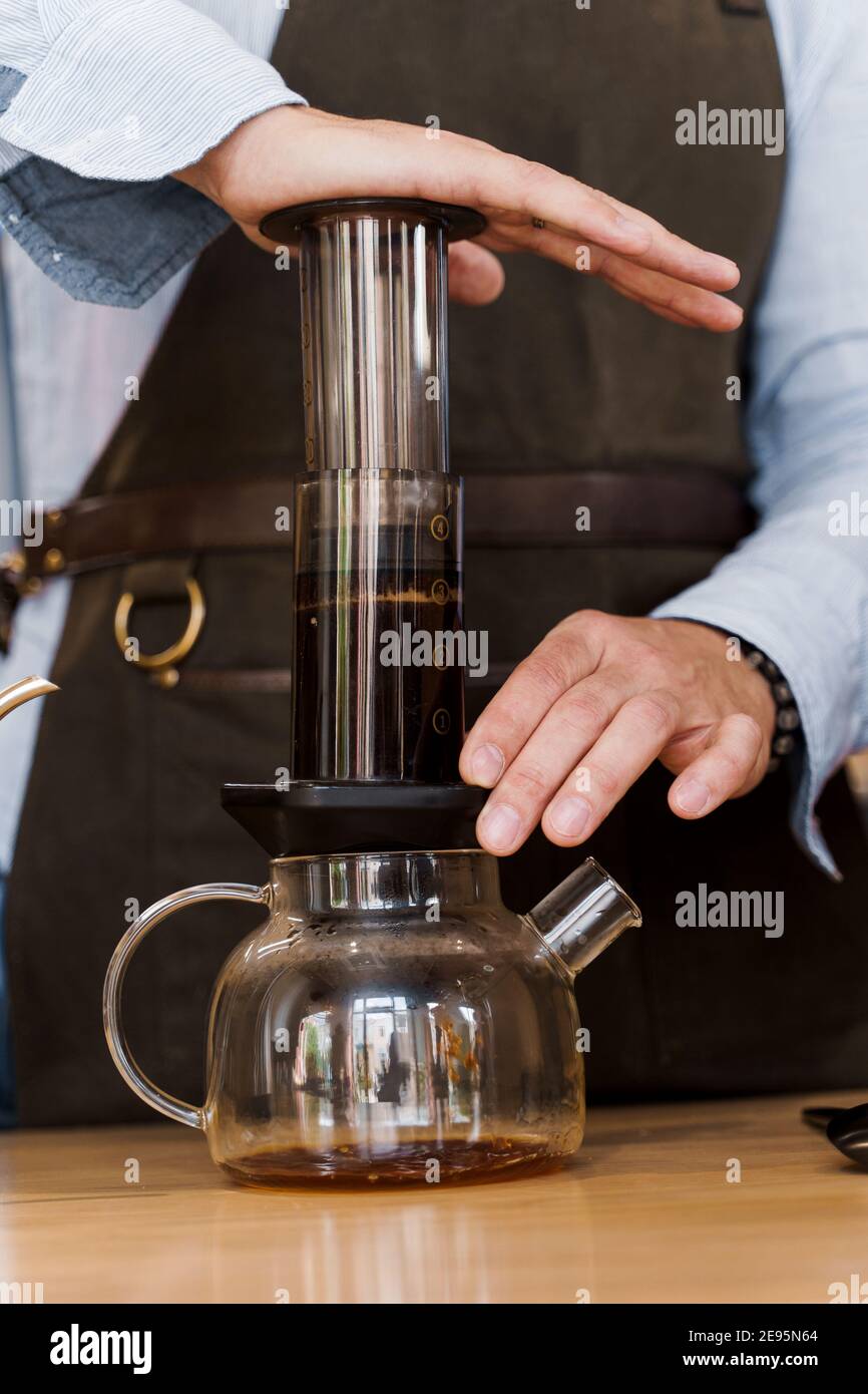 Primer plano del café de la aeropress: La prensa del barista al dispositivo  y las gotas del café pours el aire de la trought a la olla. Método  alternativo de preparación del