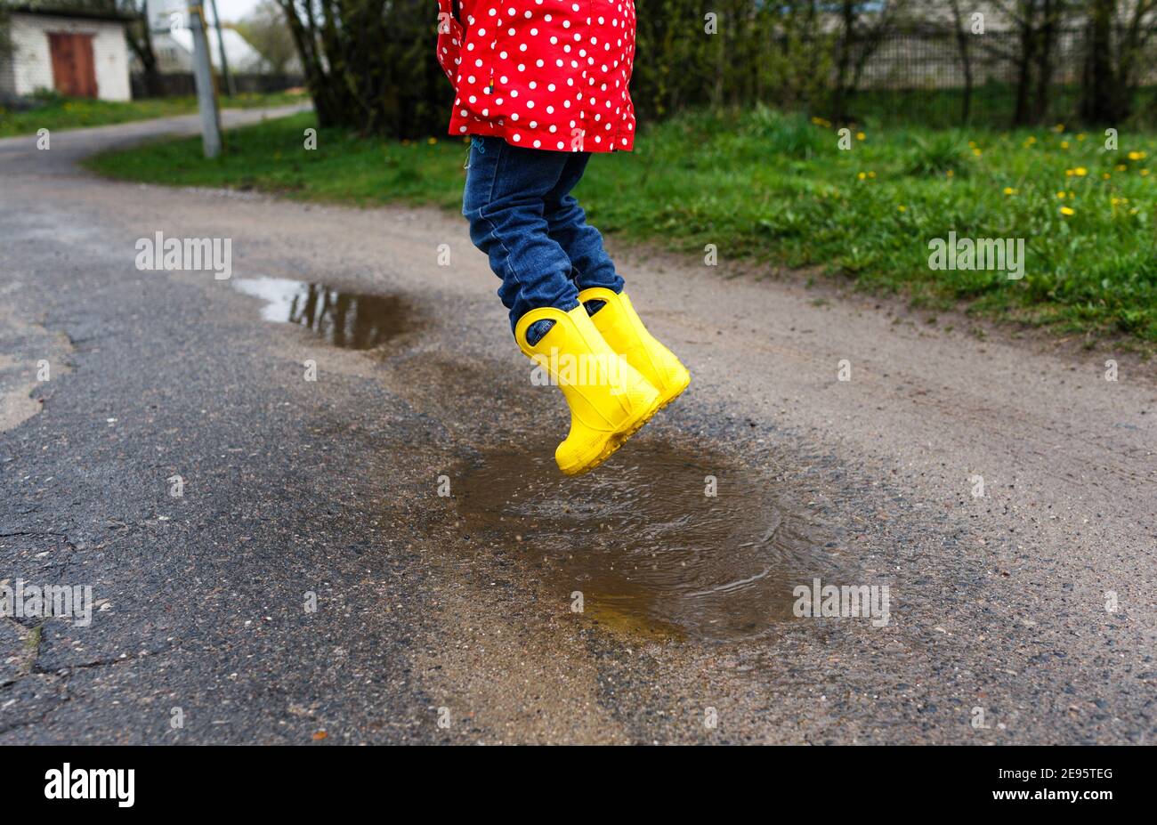 Una niña en amarillas salta en charcos primaverales, de cerca Fotografía de stock -