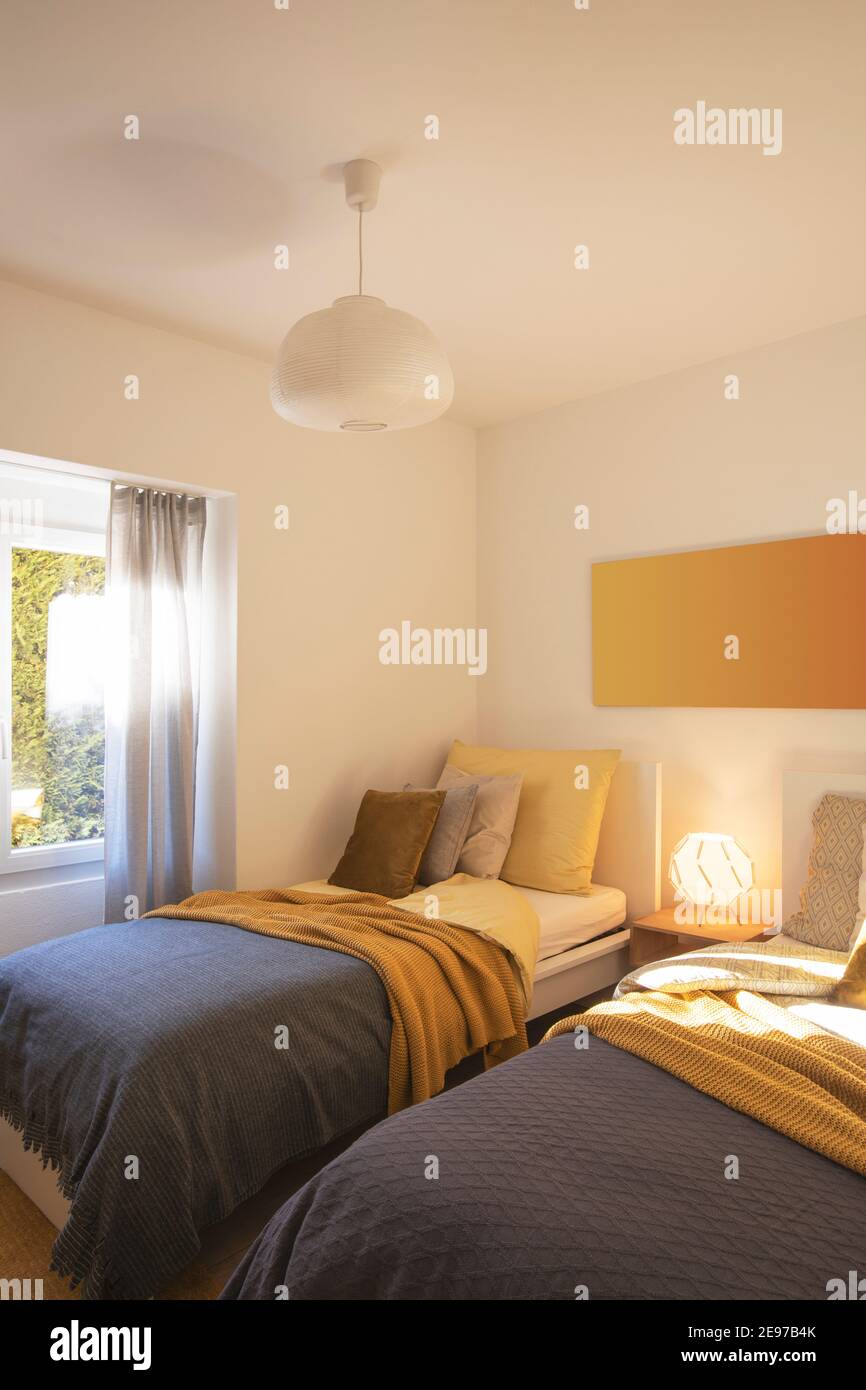 Habitación moderna con dos camas individuales con sábanas limpias y una gran almohada encima. Pared blanca. Nadie dentro. Foto de stock
