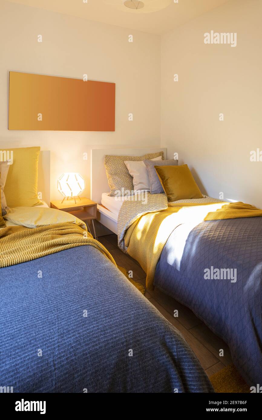 Habitación moderna con dos camas individuales con sábanas limpias y una gran almohada encima. Pared blanca. Nadie dentro. Foto de stock