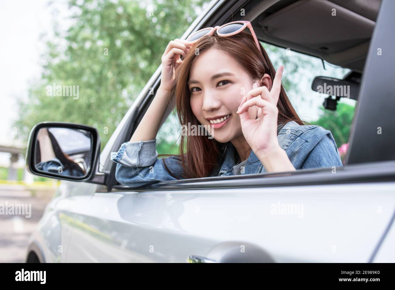 Chica guapa con gafas de sol y hacer la señal de la victoria con su mano  dentro de su coche rojo Fotografía de stock - Alamy