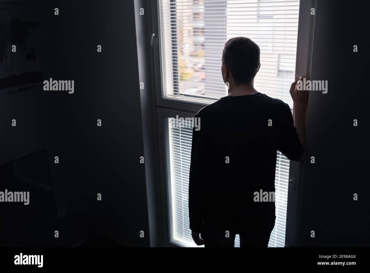 Hombre solitario mirando por la ventana. Concepto de soledad, aislamiento y soledad. Triste persona disgustada con pesar, vergüenza o estrés. Foto de stock
