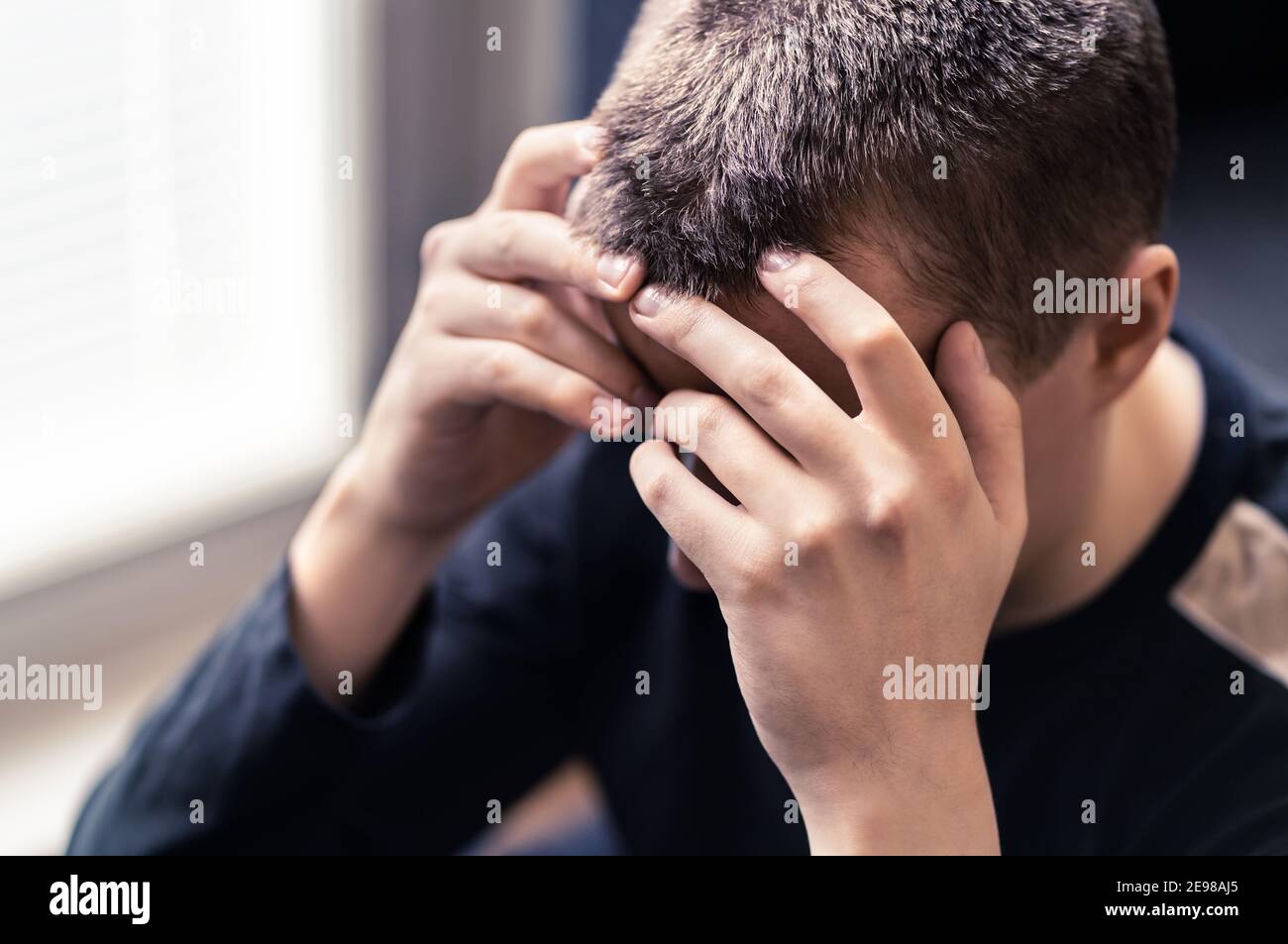 Vergüenza, pesar o desesperación. Triste joven solitario con depresión o estrés. Persona avergonzada en pena después de error. Víctima disgustada de la discriminación. Foto de stock