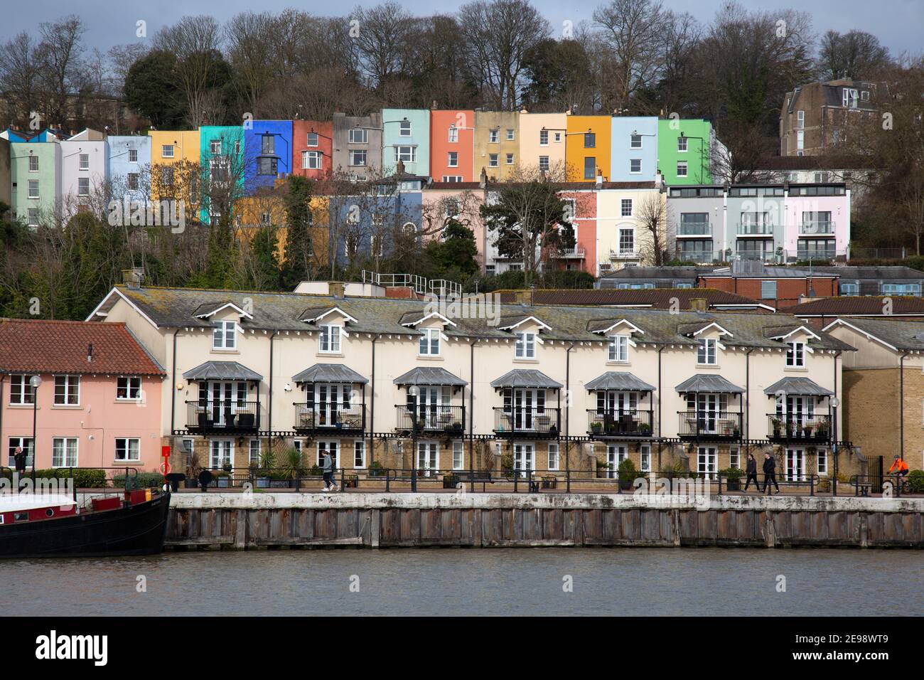 Vista al otro lado del río Avon en Bristol, Inglaterra, hacia modernos apartamentos junto al río, y coloridas casas adosadas antiguas detrás. Foto de stock