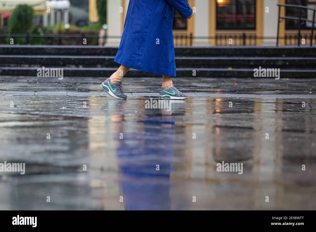 Lviv, Ucrania - 30 de septiembre de 2020: Mujer mayor con zapatillas Nike y  paraguas rojo caminando en la calle lluviosa Fotografía de stock - Alamy