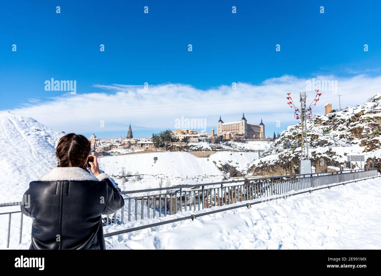 Mujer rubia con trenzas haciendo una foto en la ciudad de Toledo. Paisaje nevado de fondo. Foto de stock