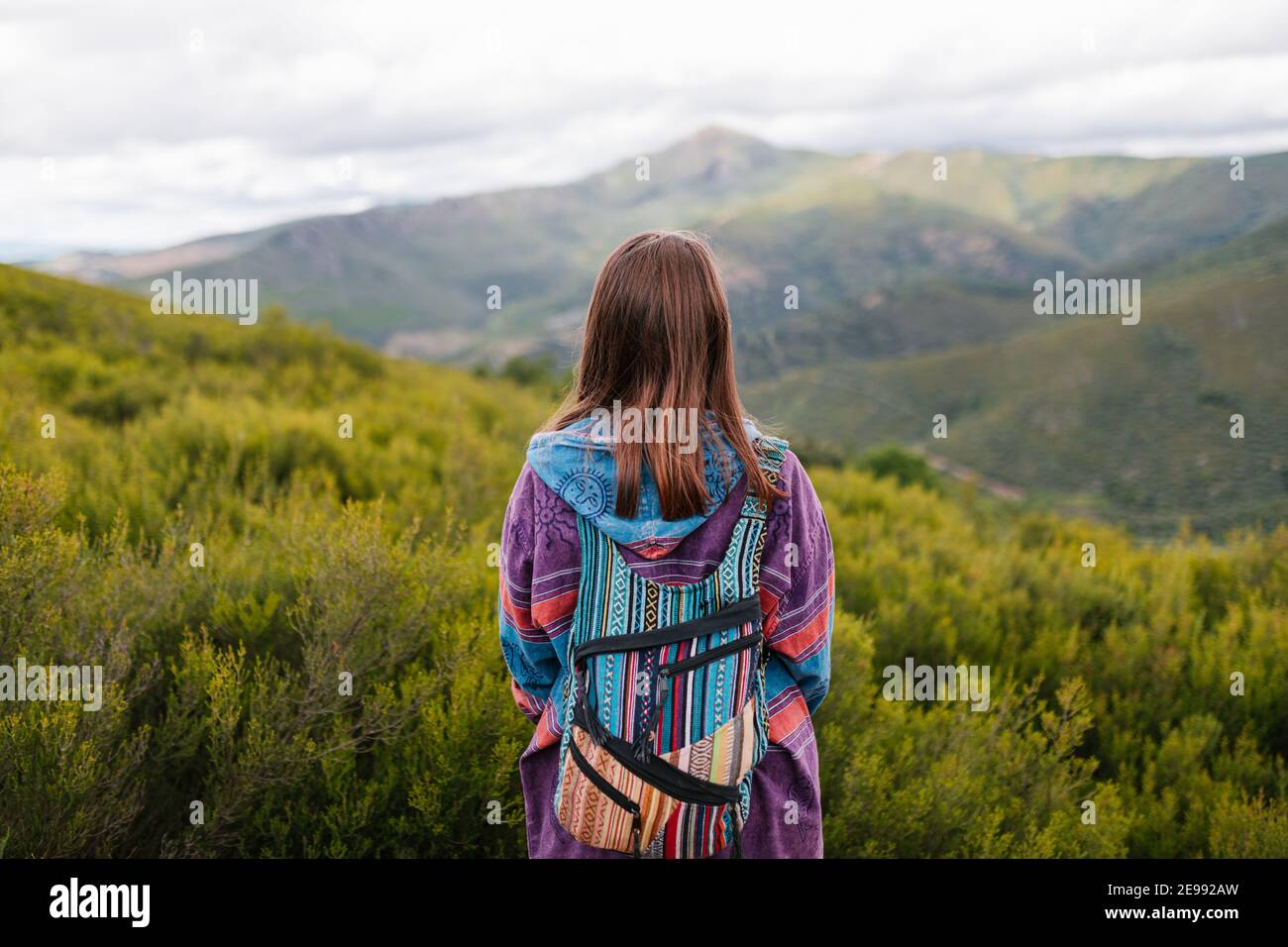 Mujer con ropa alternativa y mochila de colores mirando un gran montaña  verde Fotografía de stock - Alamy