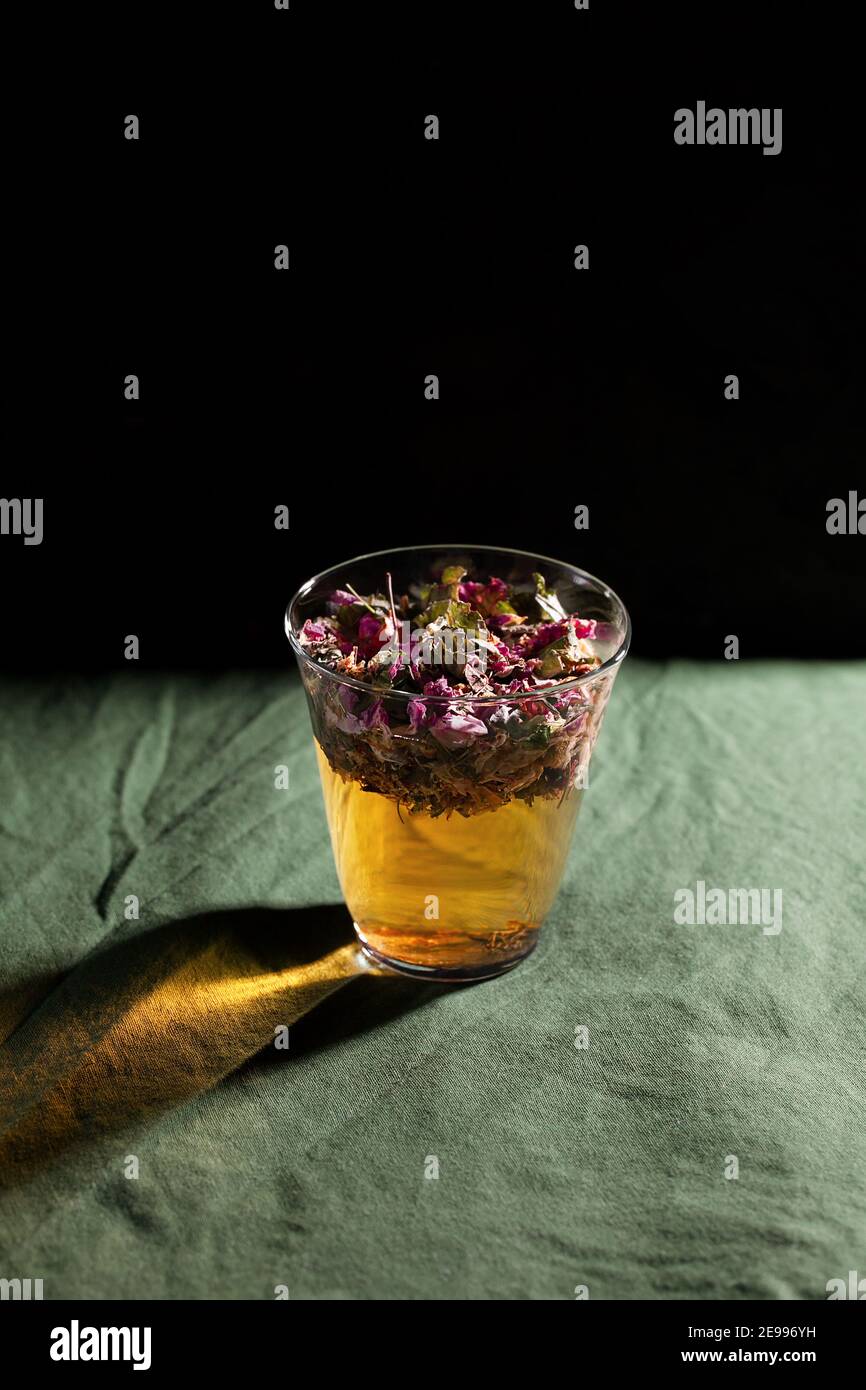 Un vaso con agua floral y herbal sobre fondo verde con espacio de copia. Concepto de remedio casero Foto de stock
