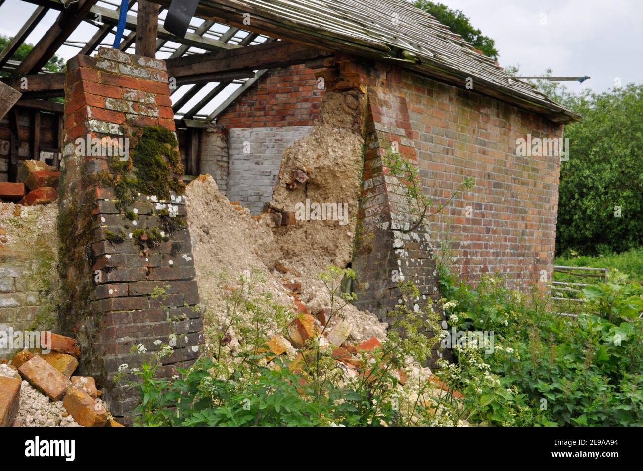 Antiguo granero de ladrillo construido con escombros de tiza se derrumba A pesar de los contrafuertes de ladrillo.Hampshire.UK Foto de stock