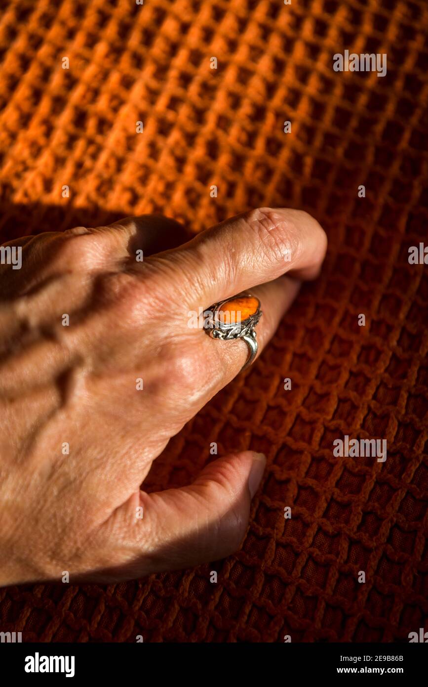 Mano femenina con un anillo naranja en una cubierta naranja Foto de stock
