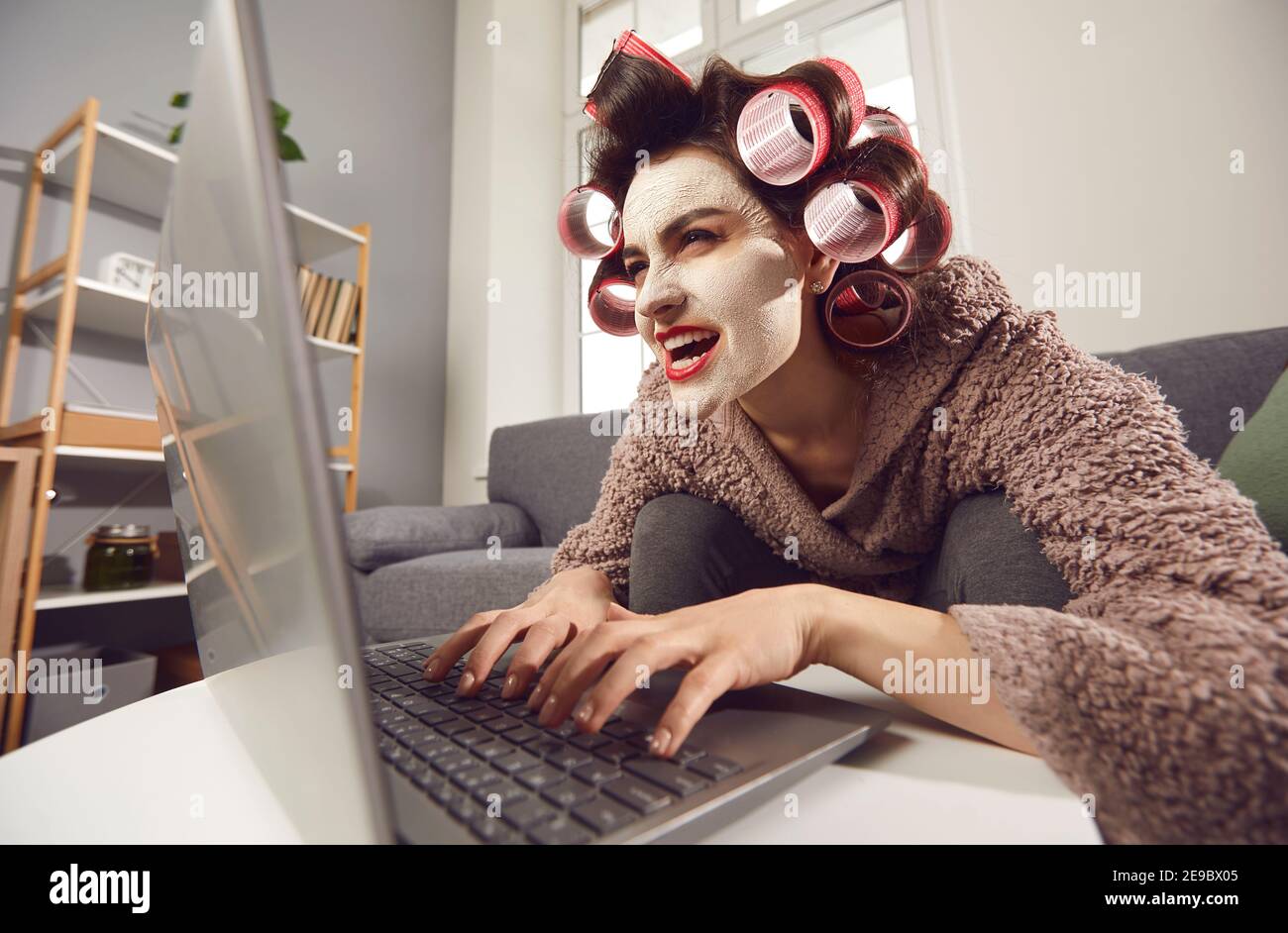 Mujer loca sentada en el ordenador portátil y dejando comentarios insultantes medios sociales de la gente Foto de stock