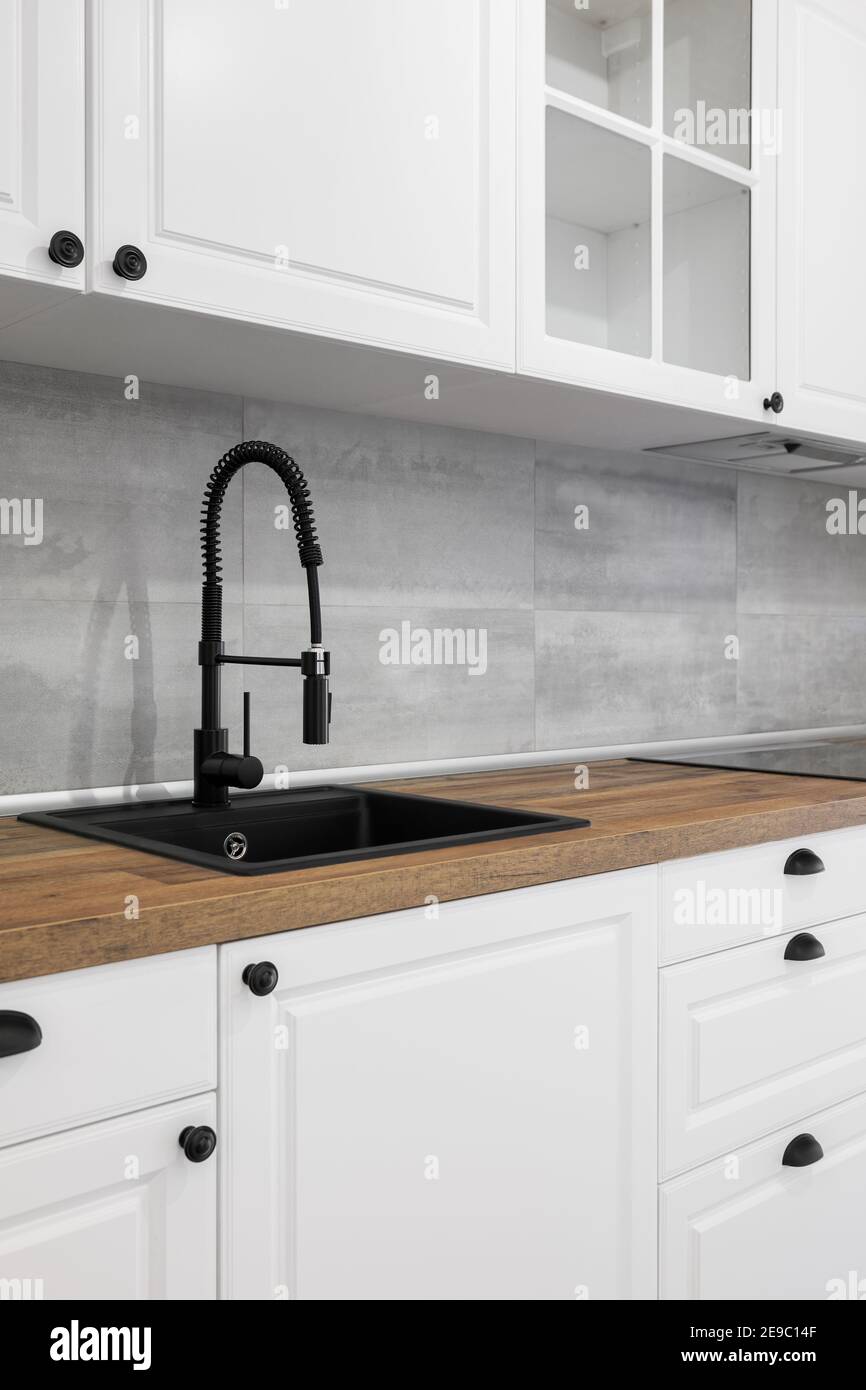 Cocina sencilla y elegante con encimera de madera, armarios blancos,  cajones y fregadero negro Fotografía de stock - Alamy