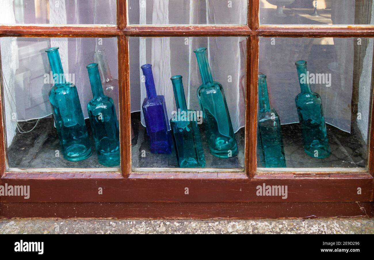 Siete botellas de vidrio azul en la pantalla en un alféizar de la ventana Foto de stock