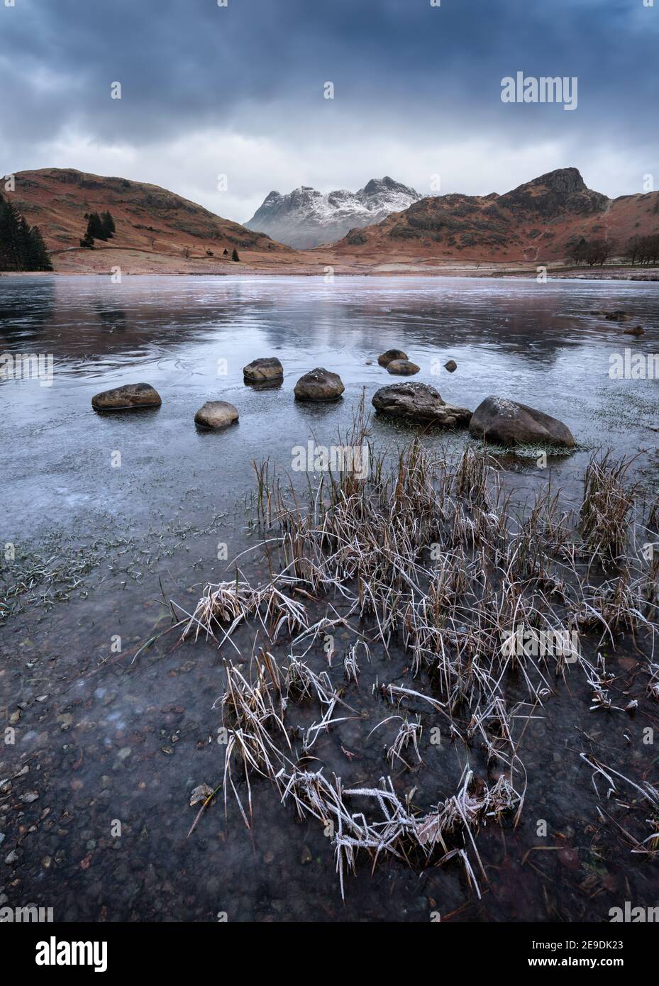 Lago congelado con hermosas vistas de las montañas nevadas en una mañana de invierno. Blea Tarn, Distrito de los Lagos, Reino Unido. Foto de stock