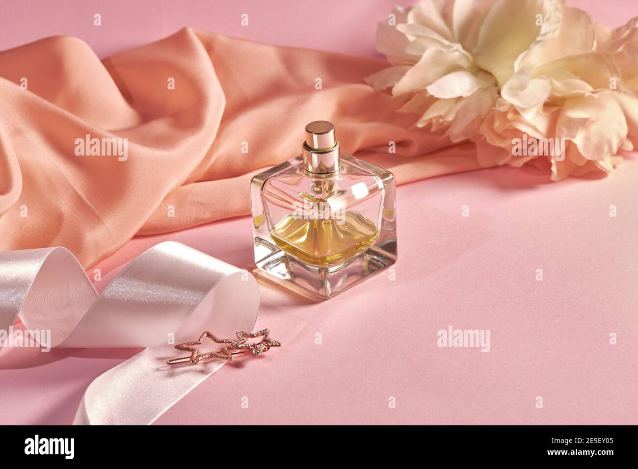 Una botella de perfume sobre un fondo rosa con tela desmenuzada, cinta de  satén blanca y un pin de pelo en forma de estrella. Tema de primavera  Fotografía de stock - Alamy