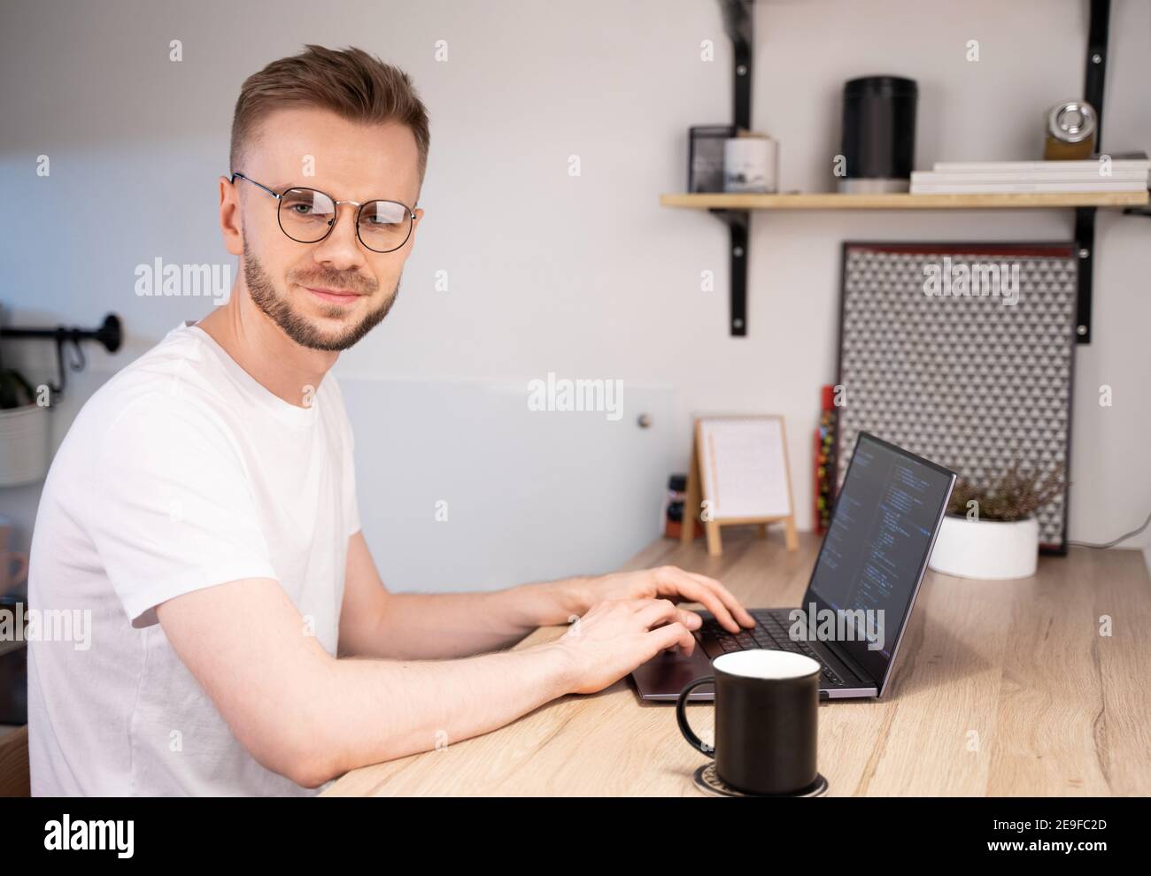 Retrato de programador masculino usando programas Código de computadora en un hogar brillante. Día del programador de conceptos Foto de stock