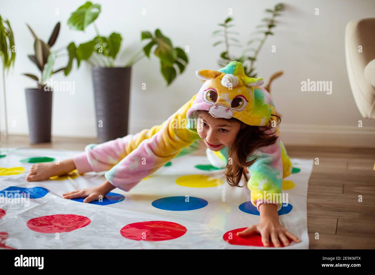 la niña está jugando twister en pijamas kigurumi Foto de stock