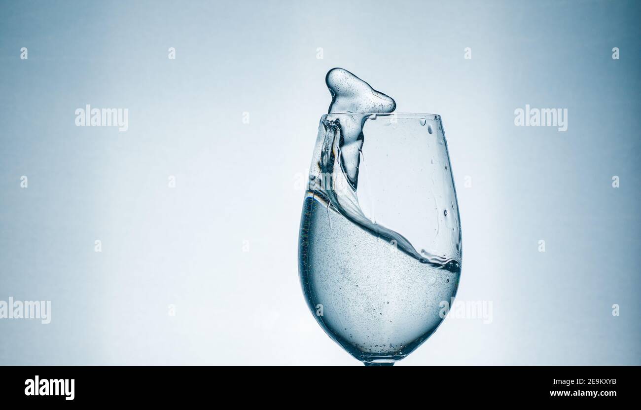Agua clara en un vaso, delicioso manantial transparente con un chapoteo en el cristal Foto de stock
