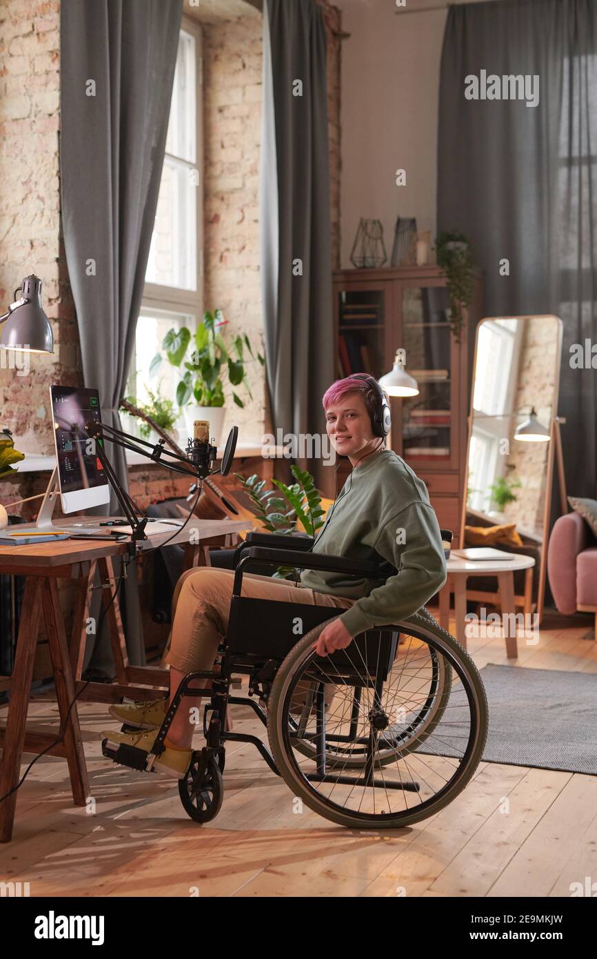 Ingeniero de sonido discapacitado en silla de ruedas escribiendo y grabando nueva canción en casa Foto de stock