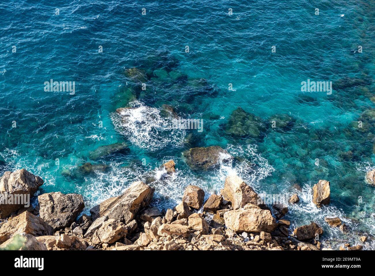 Marina. Olas rompiendo en rocas, vista rocosa de la costa desde arriba, día soleado Foto de stock