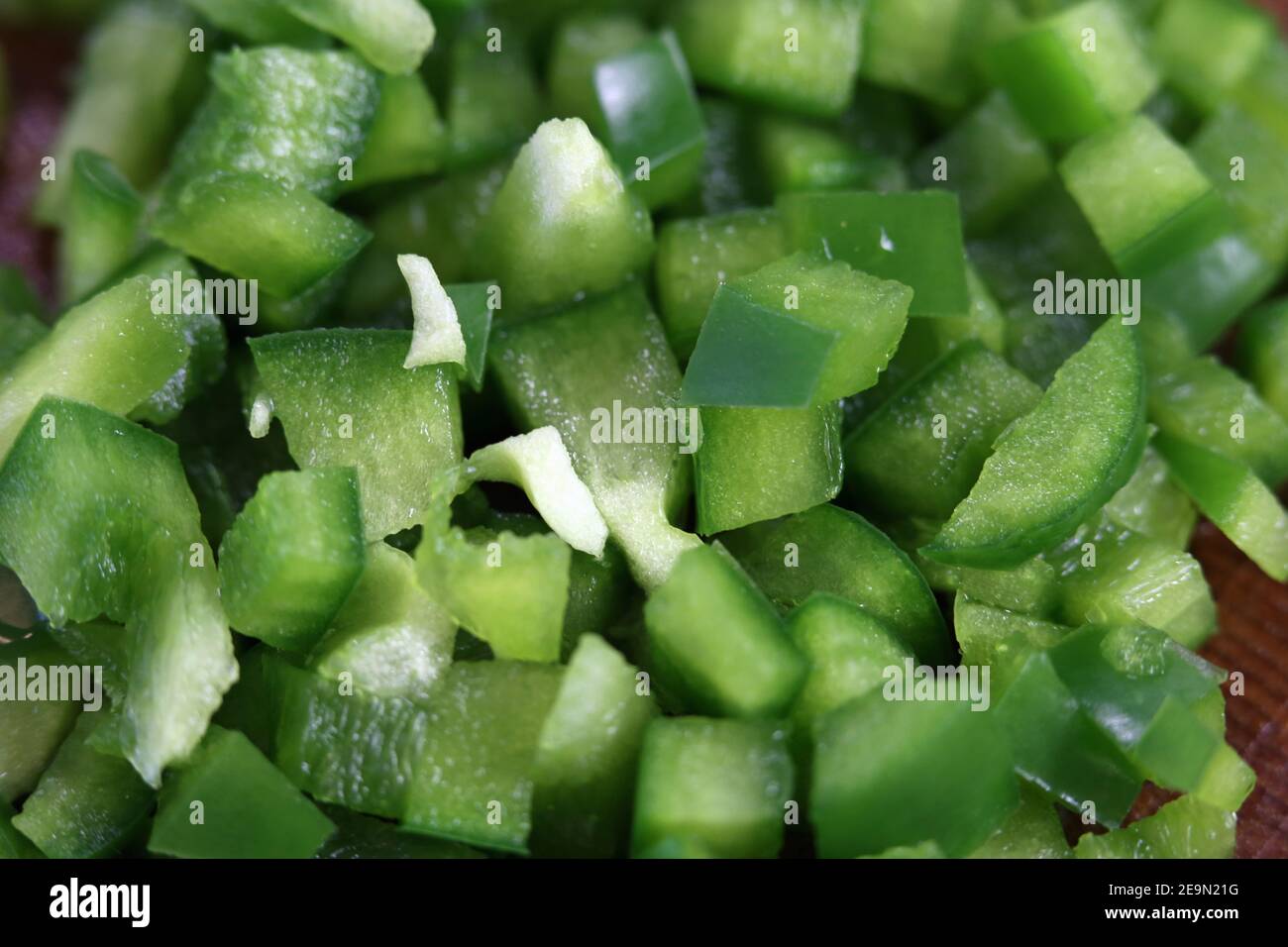 Preparación de alimentos para cocinar: Trozos picados de pimienta verde en un primer plano. Verduras saludables para una ensalada o una tortilla. Cocina casera. Foto de stock