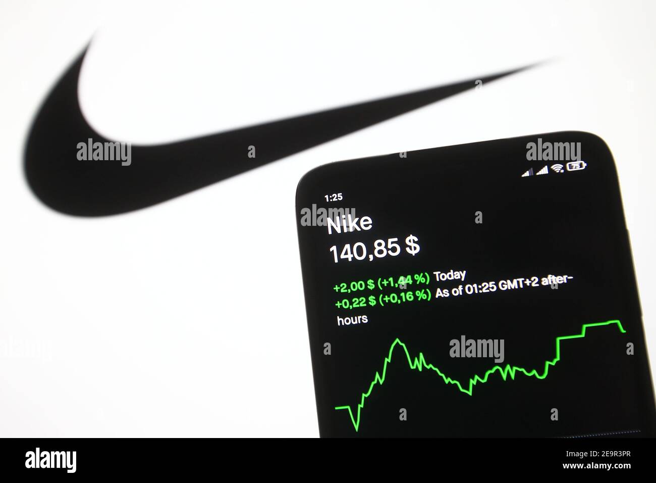 En esta ilustración de la foto se ve un logotipo de Nike delante del precio  de las acciones y un gráfico en la pantalla de un teléfono móvil Fotografía  de stock -