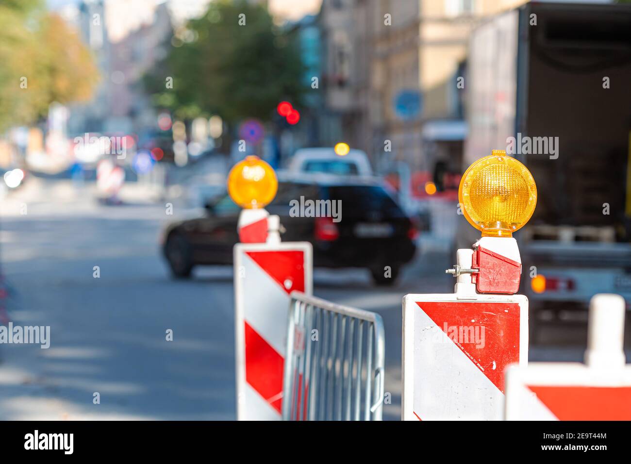 postes de advertencia con señal de luz naranja en la carretera sobre trabajos de reparación, calle borrosa con los coches sobre el fondo Foto de stock