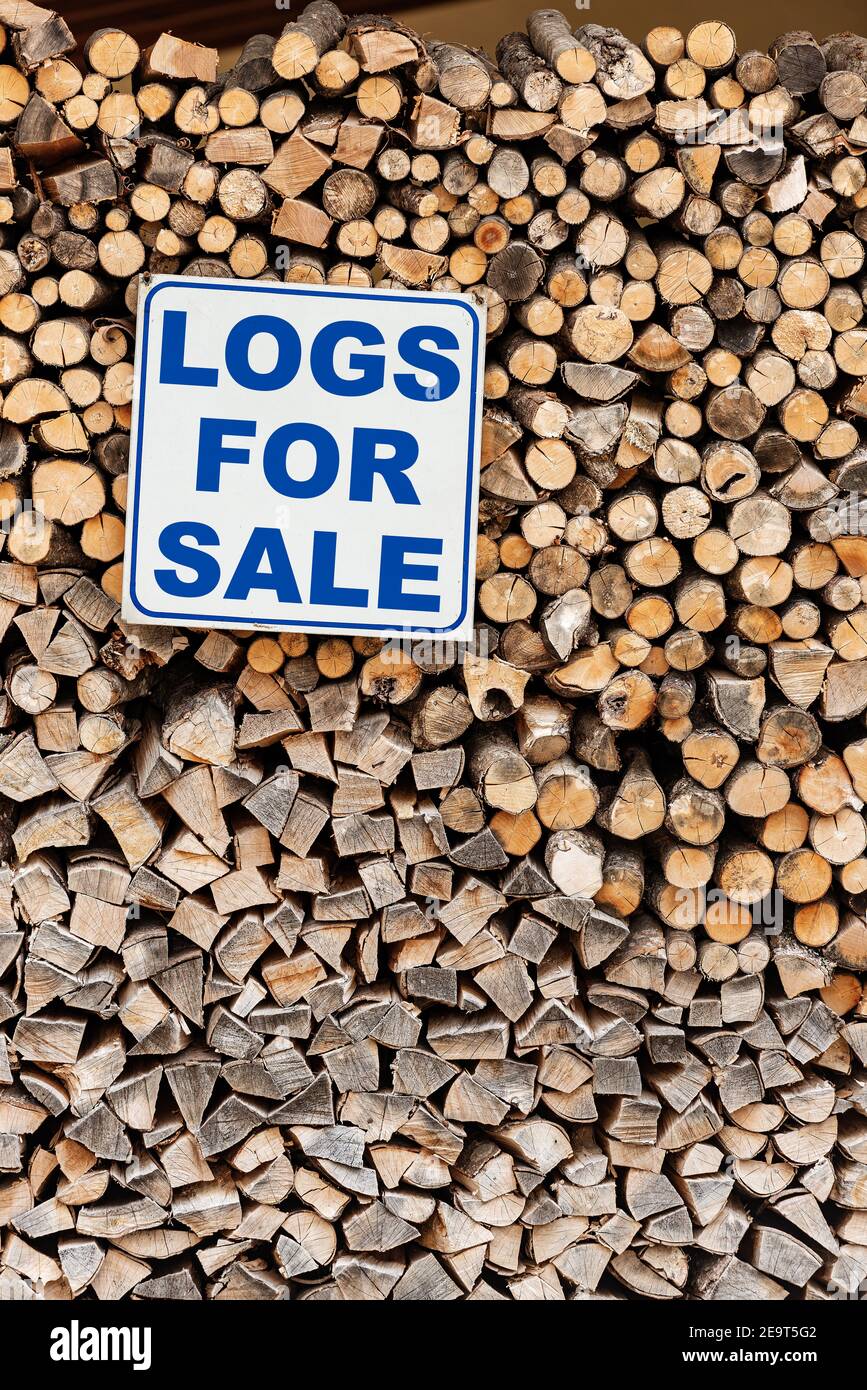 Cierre de una pila de leña con un signo comercial con la frase corta, Logs for Sale, en inglés. Foto de stock
