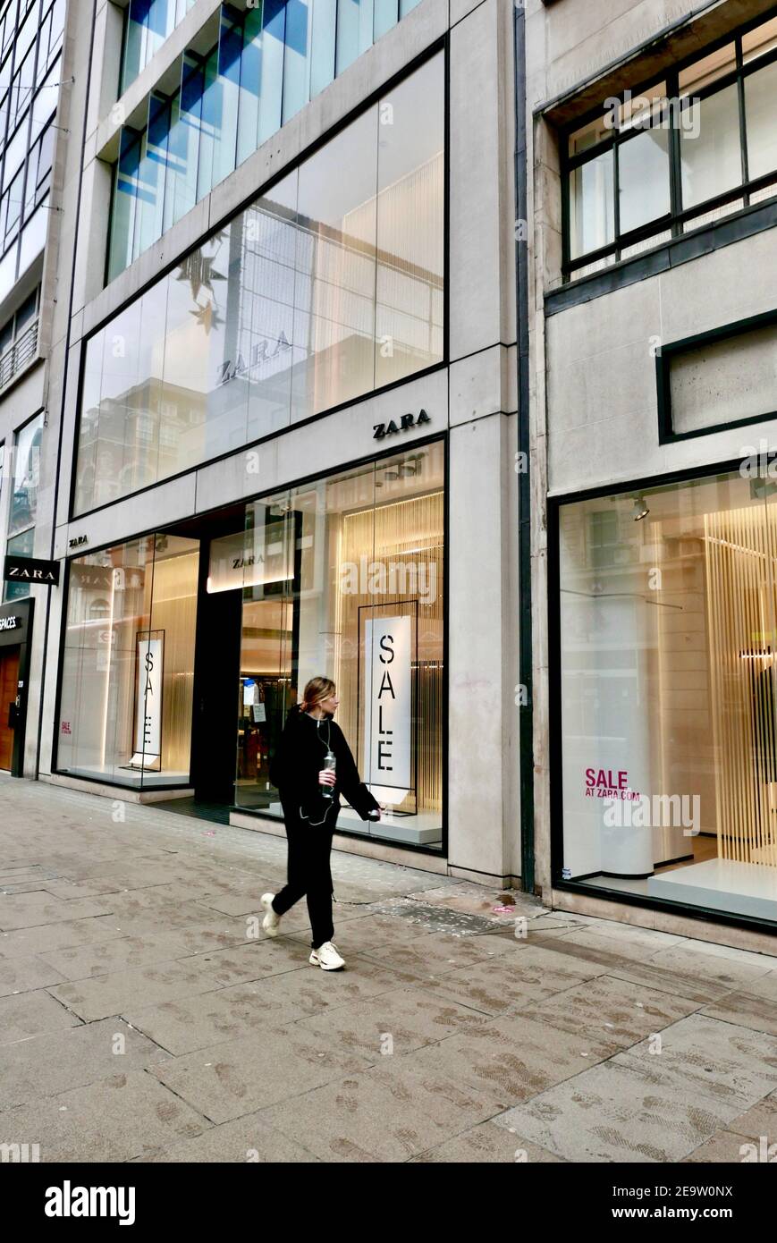 Una mujer joven pasa por la tienda de ropa Zara actualmente cerrada debido  al cierre de la pandemia de covid19 que está afectando a la economía.  Regent Street, Londres, Reino Unido Fotografía