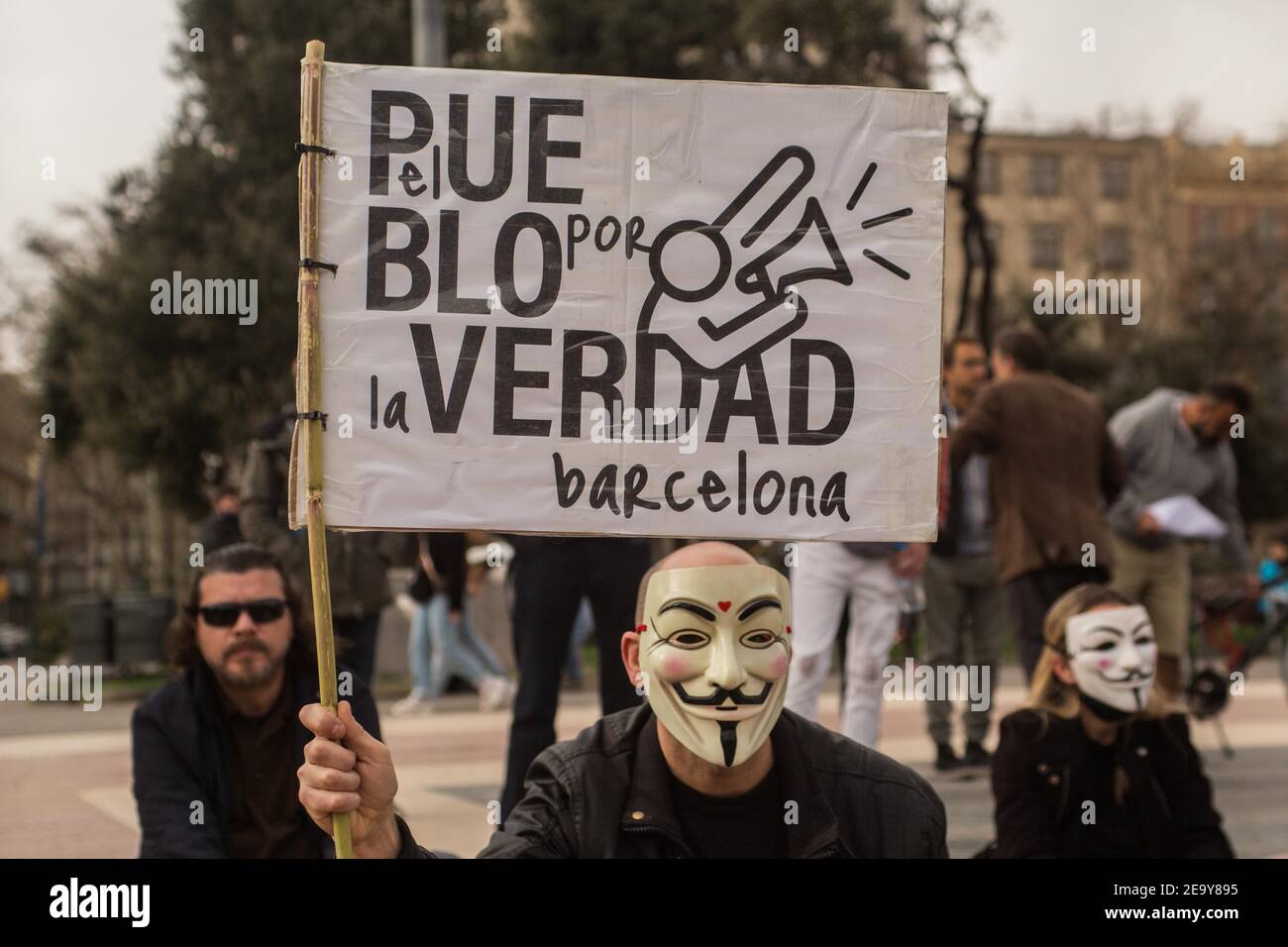 Un manifestante con una máscara de la novela gráfica británica, V por Vendetta y una pancarta que dice, la gente por la verdad, Barcelona, durante la manifestación.políticas por la Libertad (policía por la libertad) han llamado a una manifestación de negación donde han meditado, Cantó canciones y pidió el fin de las restricciones Covid-19. Foto de stock