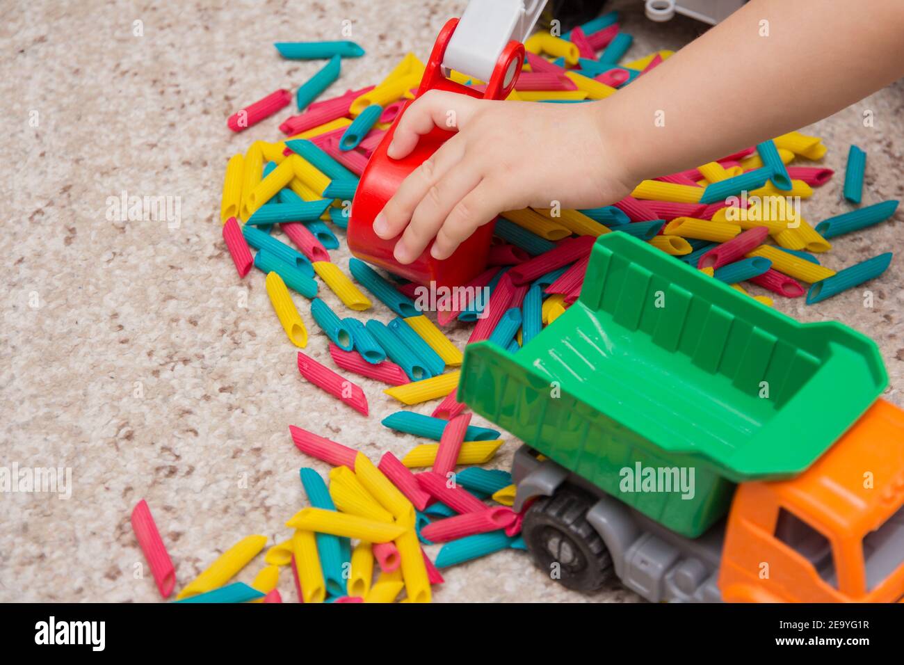 Juego infantil que en fideos pintados en colores y un camión de juguete. Juegos para niños. Desarrollo infantil. Juegos táctiles para bebés Fotografía stock - Alamy