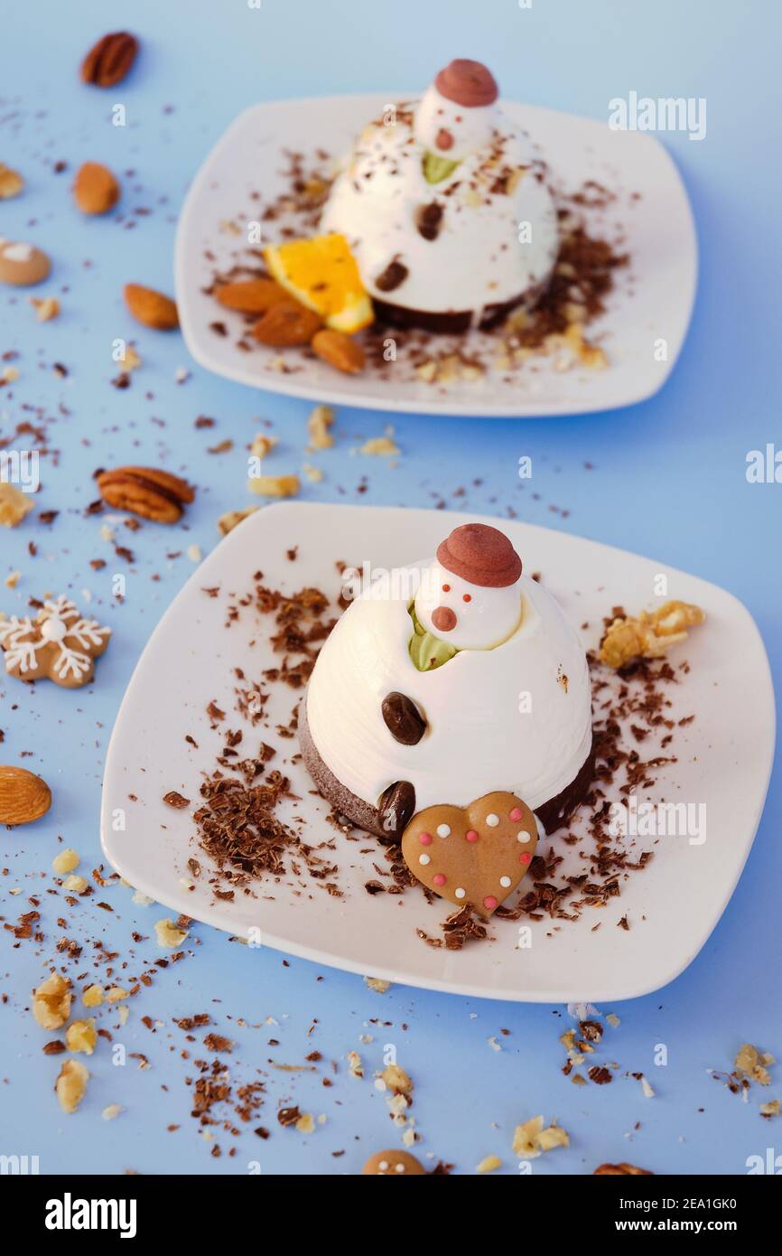 Fondo helado en forma de dos muñecos de nieve comestibles en platos blancos de cerca. Vista superior. Idea creativa para postres festivos de Navidad y Año Nuevo Foto de stock