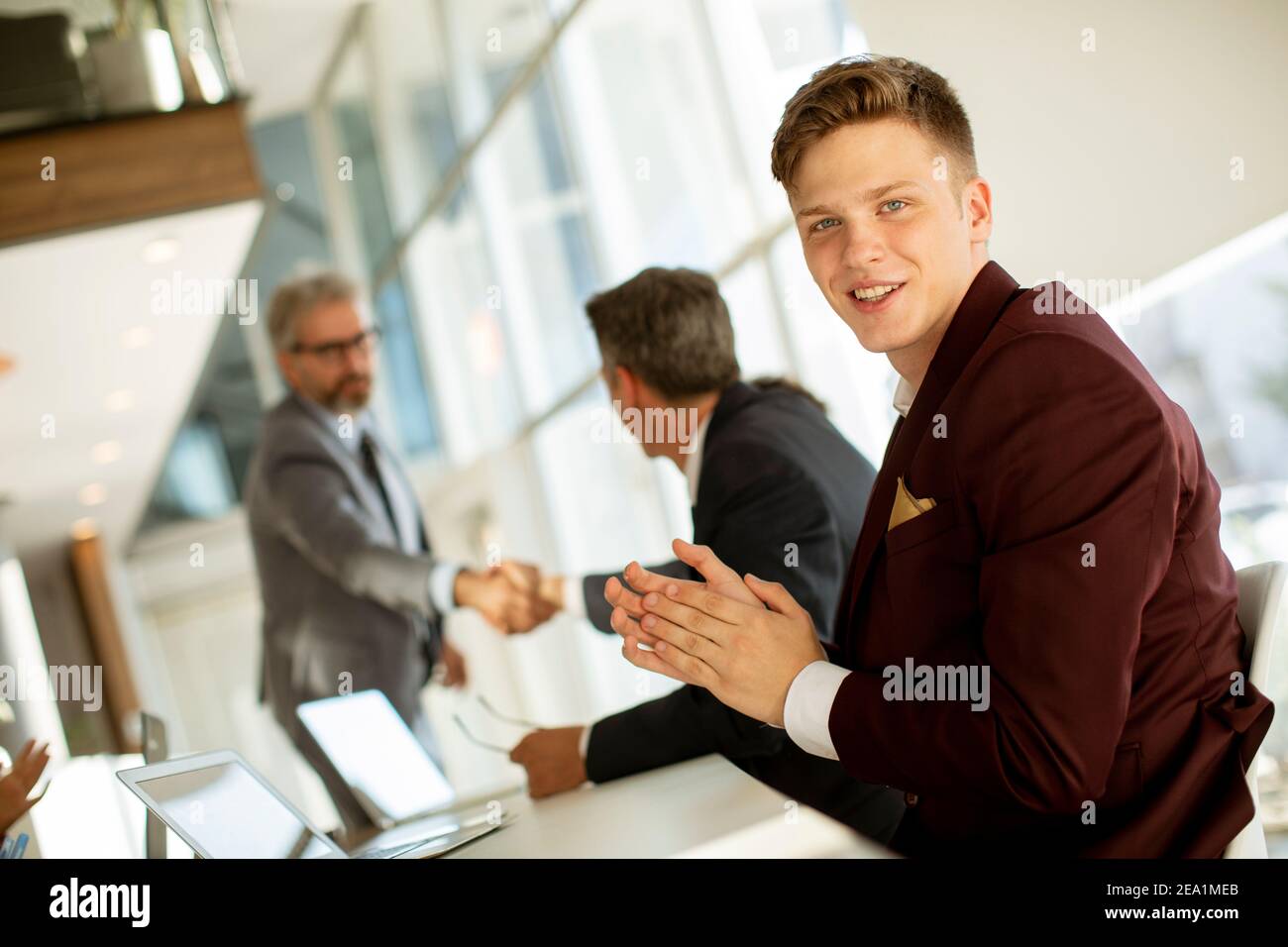 Un hombre joven y guapo golpeando las manos después de una exitosa reunión de negocios la oficina moderna Foto de stock