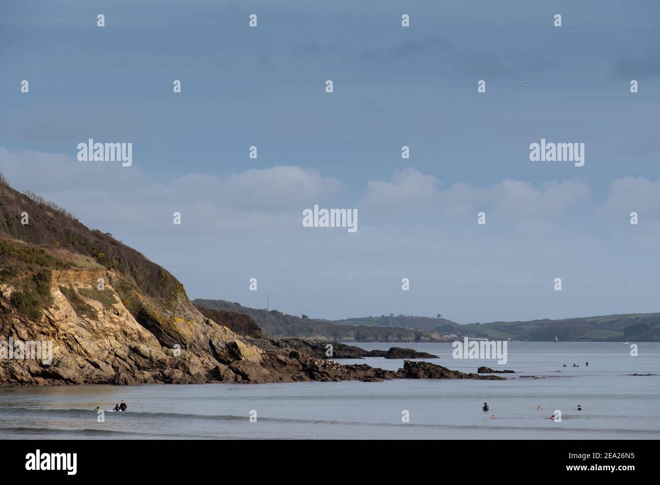 Algunos caminantes y nadadores bien espaciados en la playa de Maenporth haciendo el ejercicio permitido durante el cierre pandémico de Covid 2021 de 19. Normalmente lleno de gente. Foto de stock