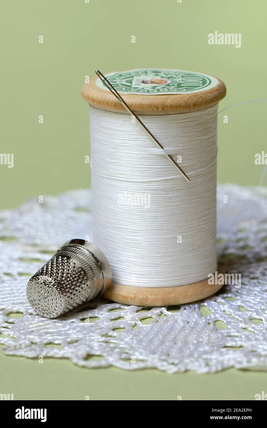 Hilo de rosca con aguja de coser y dedal Foto de stock