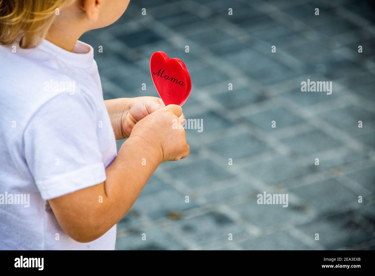 Niño con un corazón en las manos para darle a su madre para el día de la madre Foto de stock