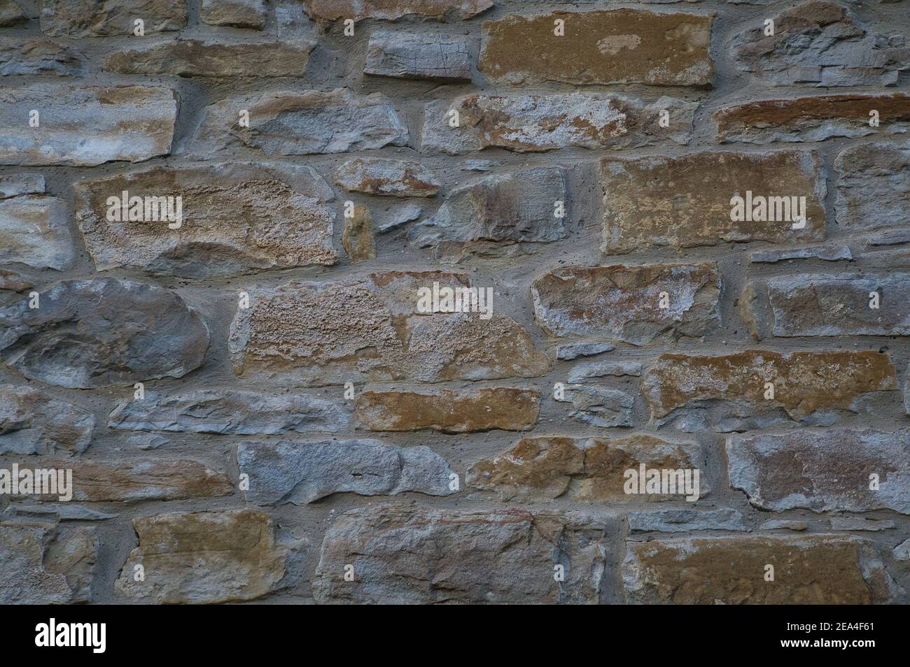 Pared de piedra de piedras naturales en diferentes tamaños; chapa de piedra rústica en tonos de marrón y beige; cubierta de pared con piedras naturales, azul Foto de stock