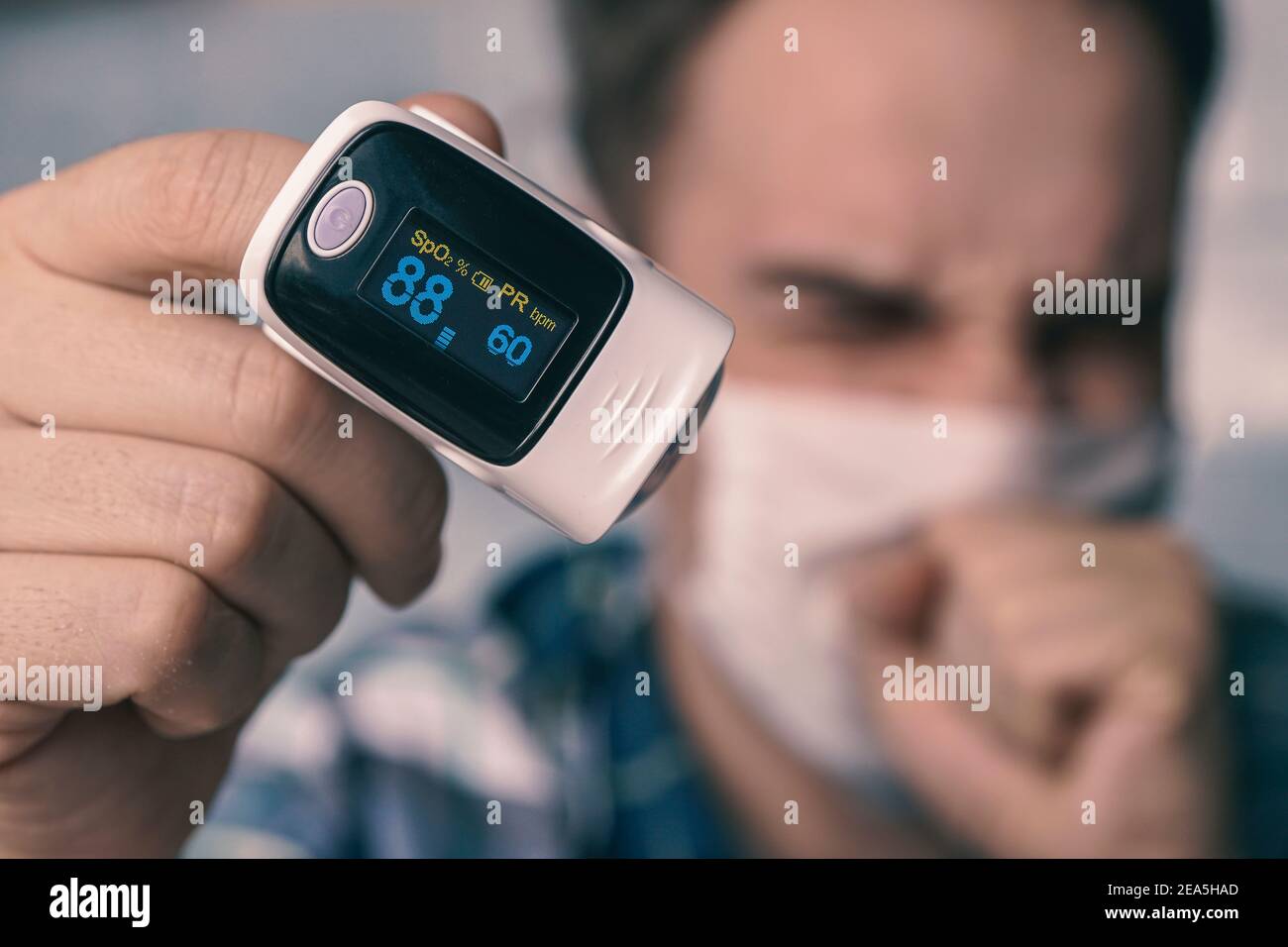 oxímetro de pulso en el dedo del hombre. saturación de oxígeno de la sangre.  Un paciente en una máscara médica mide la saturación de sangre con una  oximetría de pulso electrónica Fotografía