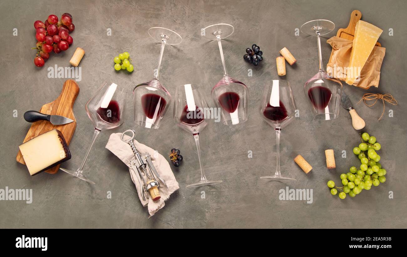 Variedad de vinos y bocadillos. Diferentes tipos de uvas. Ingredientes frescos sobre fondo gris. Vista superior Foto de stock