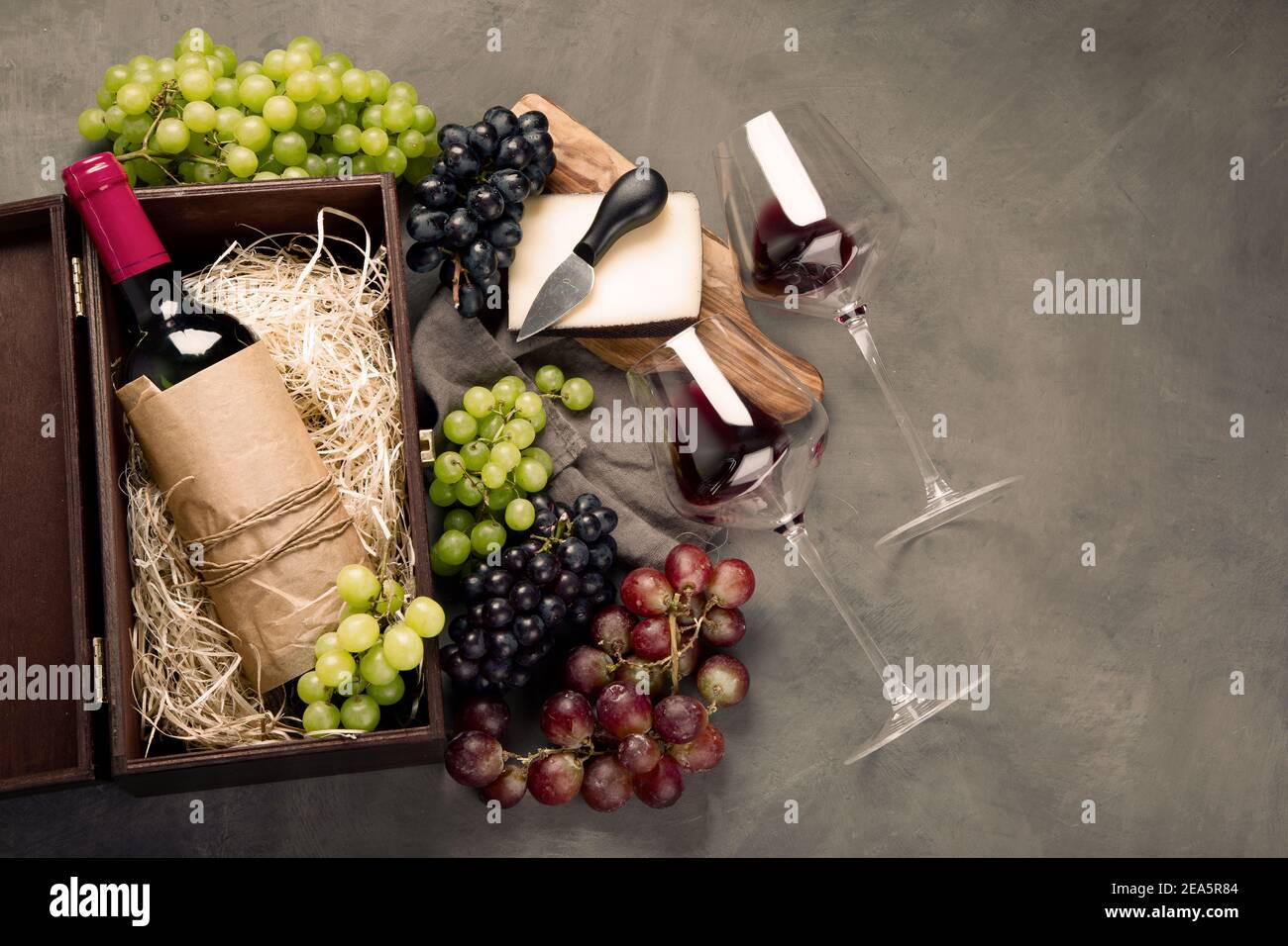 Variedad de vinos y bocadillos. Diferentes tipos de uvas. Ingredientes frescos sobre fondo de madera. Vista superior Foto de stock