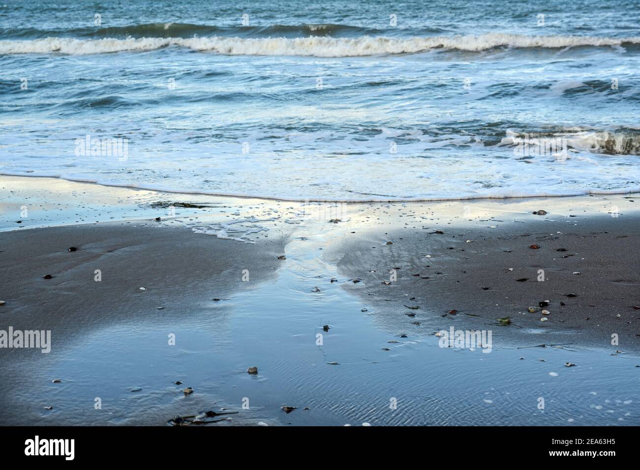 Playa de mar con olas azules y aguas poco profundas en la arena mojada, fondo marino para vacaciones y viajes temas, copiar espacio, enfoque seleccionado, estrecho de Foto de stock