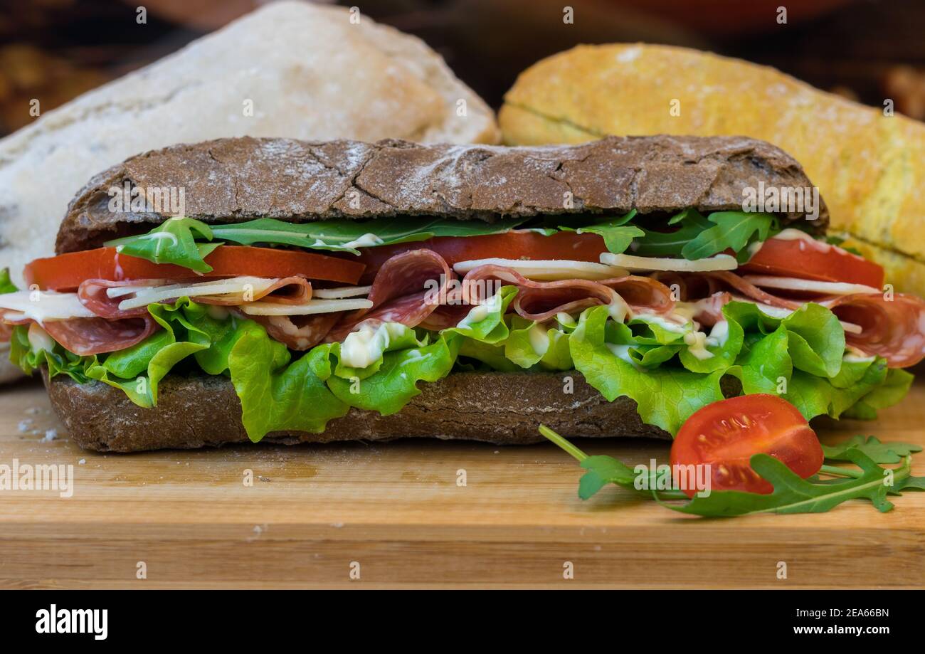 Disparo estático de un ligero rollo de pan de pavo y un oscuro sándwich balcánico, con sallad Foto de stock
