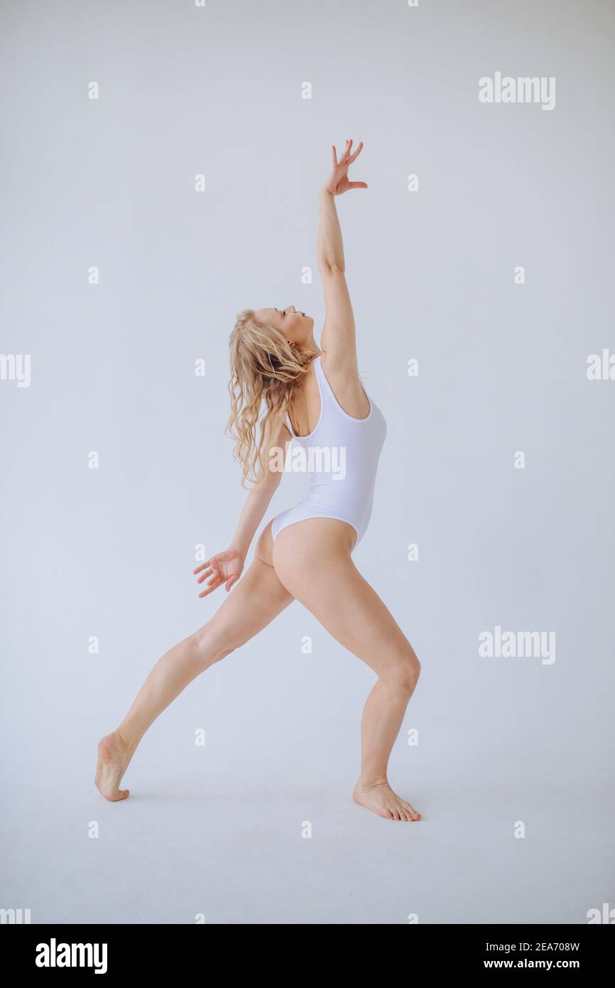 Gimnasta femenina en un leotardo blanco bailando en un estudio Foto de stock