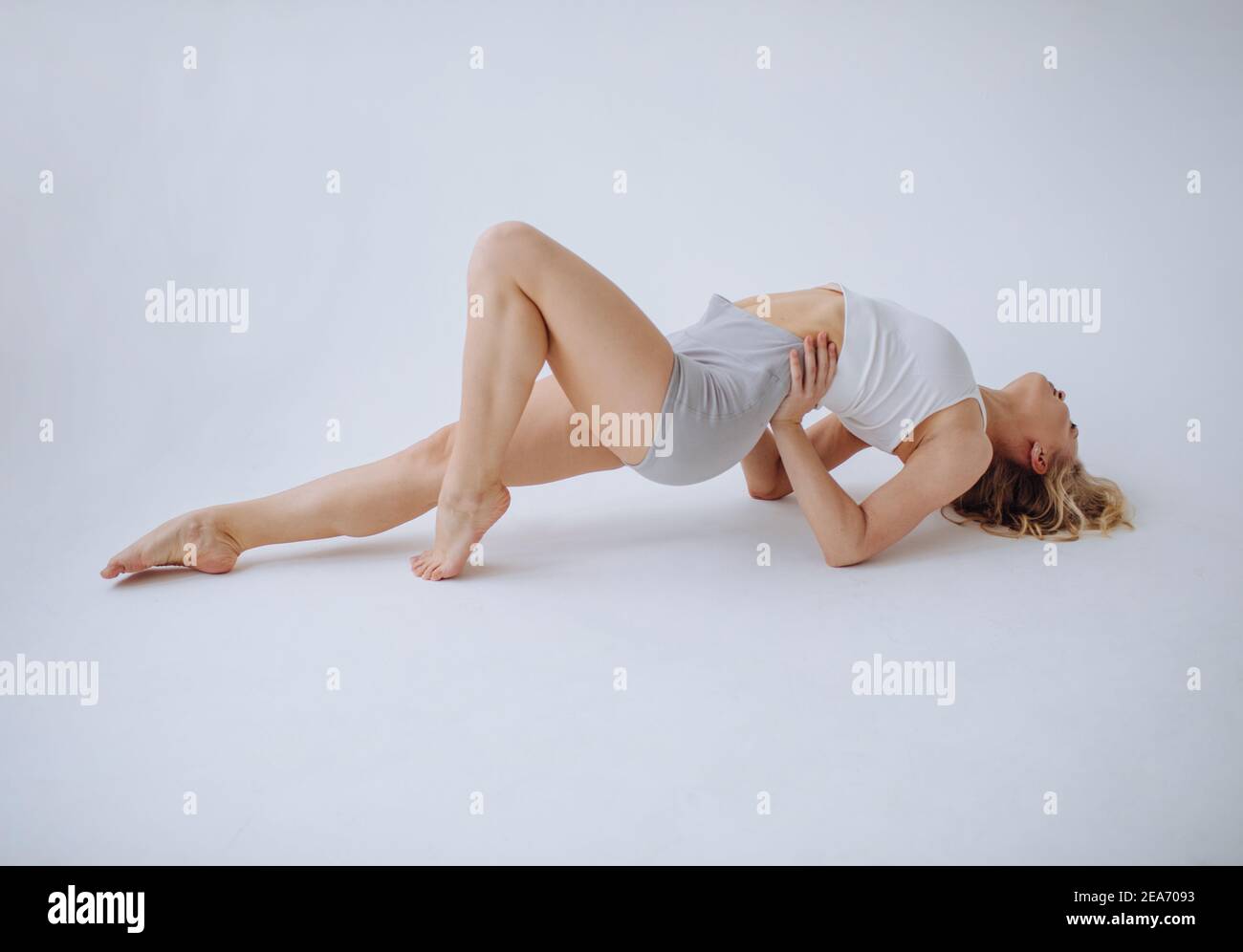 Gimnasta femenina acostada en el suelo estirándose en un estudio Foto de stock