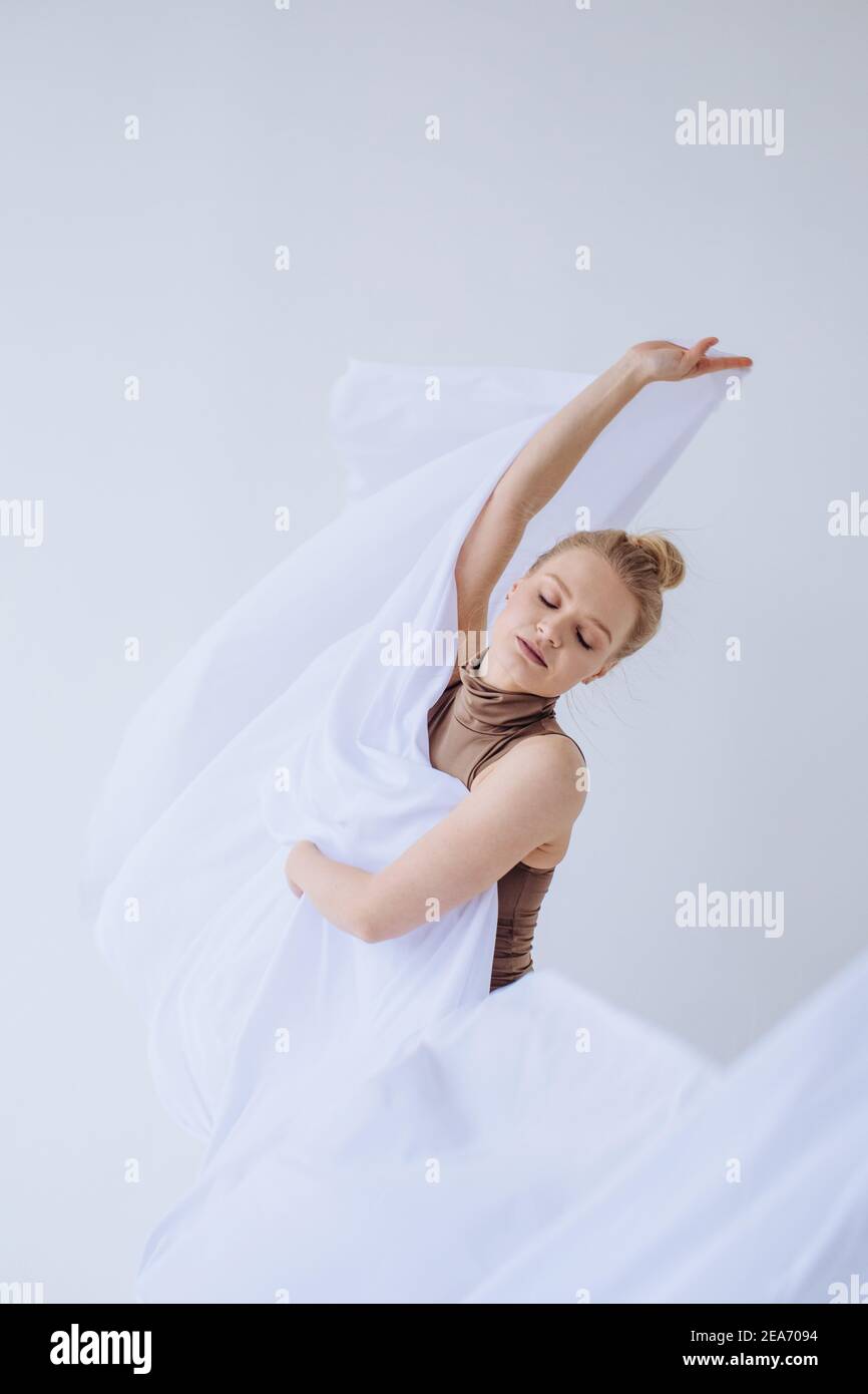 Mujer bailando con tela blanca en un estudio Foto de stock