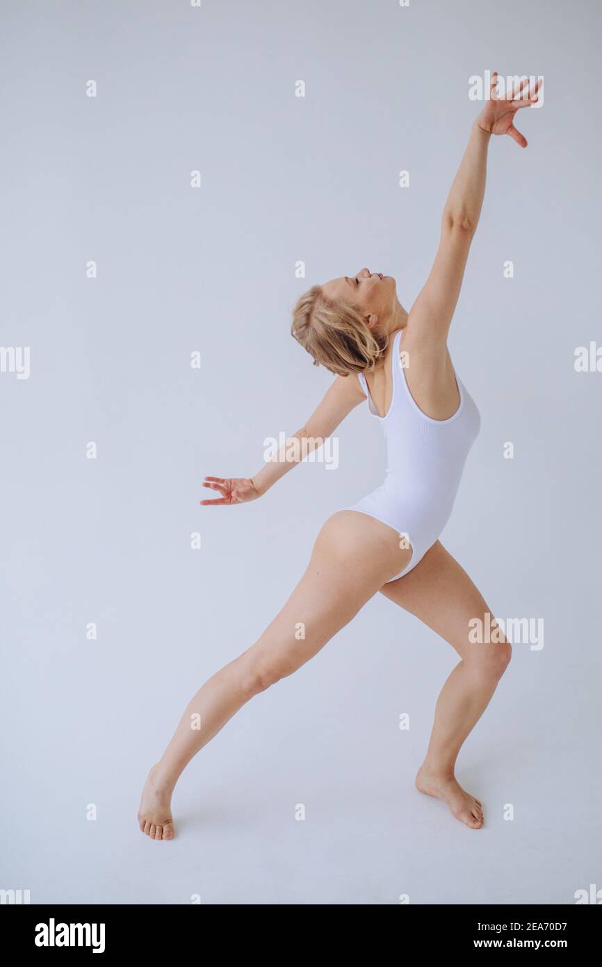 Gimnasta femenina en un leotardo blanco bailando en un estudio Foto de stock
