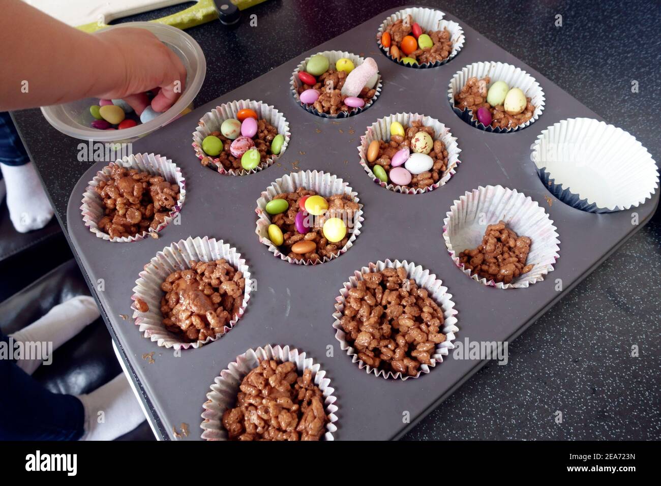 Los niños hacen y adornan pasteles de arroz de chocolate con maratías y mini huevos Foto de stock