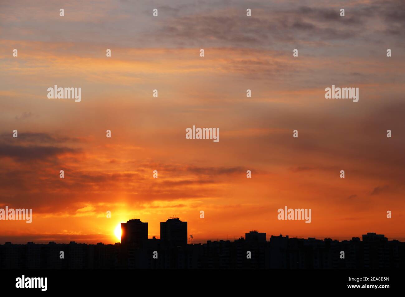 Puesta de sol sobre la ciudad, vista panorámica. Puesta de sol y cielo naranja con espectaculares nubes sobre las siluetas de los edificios residenciales Foto de stock